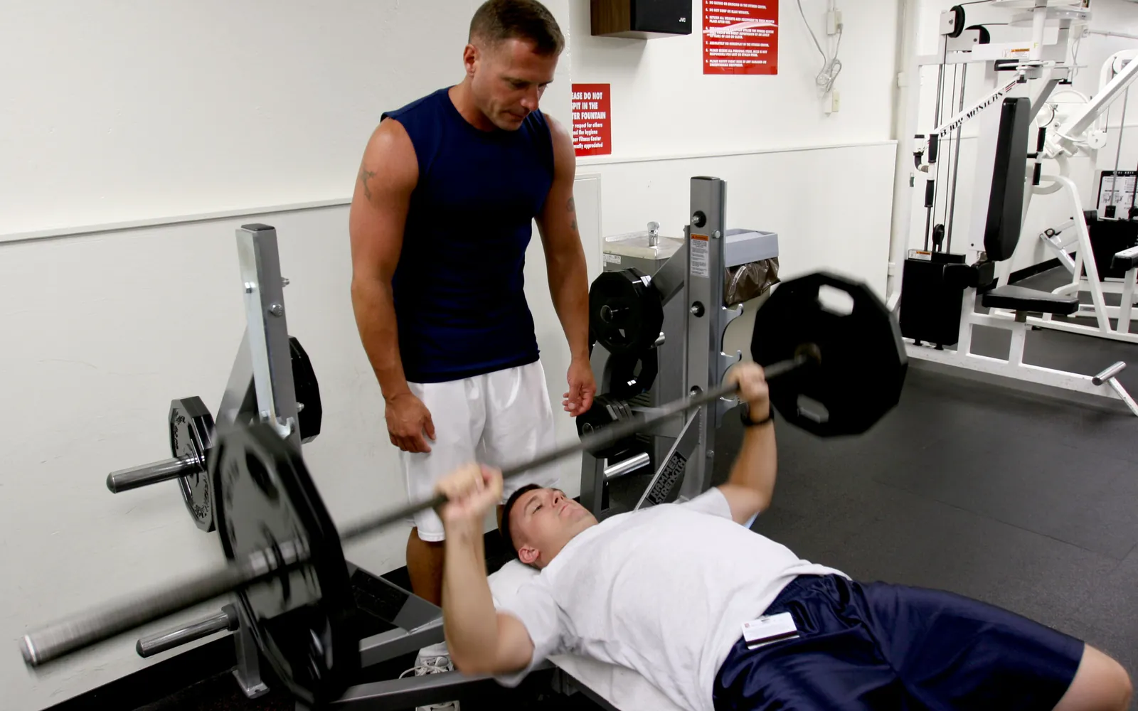 Personal trainer che assiste un cliente durante un esercizio di forza